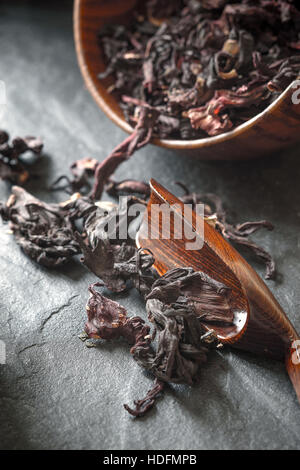 Hibiscus tea dans le bol en bois sur la pierre sombre table verticale Banque D'Images