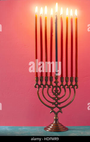 Hanukkah menorah avec bougies allumées sur la verticale sur fond rose Banque D'Images