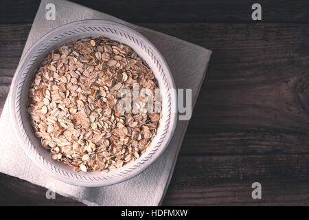 Les flocons d'avoine dans le bol sur la table en bois Vue de dessus Banque D'Images
