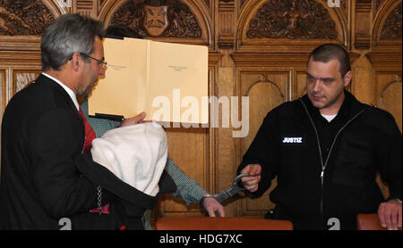 L'accusé Alperen T. nous tend un dossier pour couvrir son visage dans le tribunal de district à Brême, Allemagne, le 12 décembre 2016. Son avocat Armin von Doellen (L) et un agent de la justice le guider de son siège. Le ministère public accuse l'artiste de 24 ans, étudiant de l'exécutant sur une période de 75 ans avec sa moto pour les piétons qui traversent la rue au feu rouge. C'est considéré comme un meurtre, comme la moto rider aurait ensuite été filmé et chargé de l'épreuve de sa chaîne YouTube, qui a plus de 80 000 abonnés. Cela a également amené du profit grâce à la publicité. Photo : Carmen Jaspersen/dpa Banque D'Images