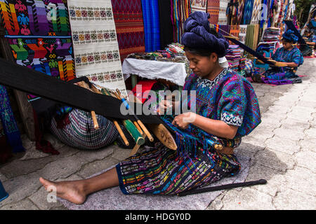 Les femmes mayas assis sur le sol et à l'aide de métiers à tisser en vêtements traditionnels à Santa Catarina Palopo, Guatemala. Banque D'Images