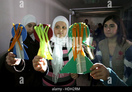 Réfugiés syriens Mariam Al Azeb, 10, (au centre) participe à un atelier de fabrication de marionnettes à l'occasion d'une classe thérapeutique géré par Lina psychologue Zaarour (à droite) à un centre de Caritas dans la région de la vallée de la Bekaa au Liban. Les classes font partie de la prise en charge psychologique données aux enfants pour les aider à surmonter le traumatisme de la guerre en utilisant les arts, l'artisanat et des jeux. Banque D'Images