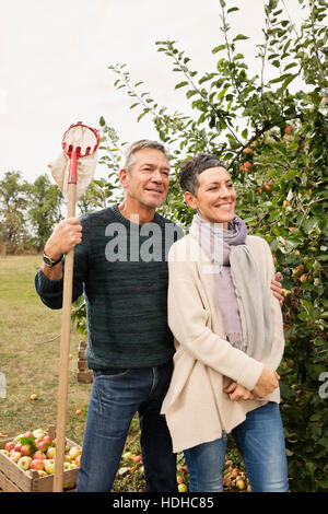 Happy couple standing avec cueilleur de fruits de verger Banque D'Images
