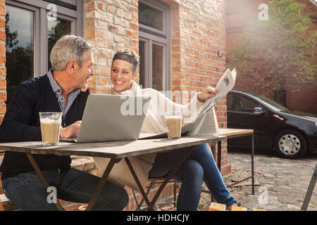 Mature Woman Reading newspaper in back yard Banque D'Images