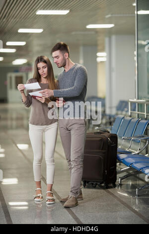 Toute la longueur du jeune couple à l'aéroport billets lecture Banque D'Images