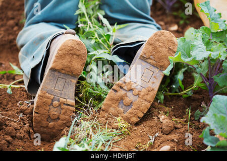 L'homme à genoux bottes dans le sol. Banque D'Images