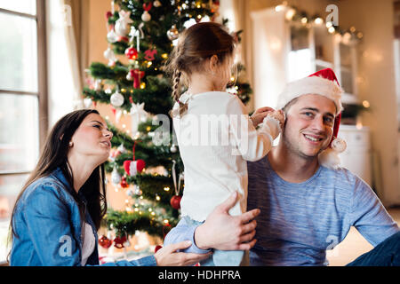 Jeune famille avec daugter à arbre de Noël à la maison. Banque D'Images