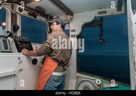 Capitaine de bateau de pêche du homard vues electronics pour aider à trouver des bouées de piège au coucher du soleil, Yarmouth Banque D'Images