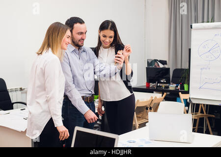 Groupe de quatre joyeux divers co-workers taking self portrait et en faisant des gestes avec les mains au drôle de petit bureau Banque D'Images