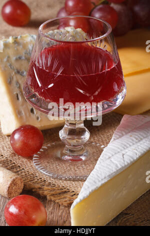 Vin rouge avec le fromage et les raisins sur la table. La verticale Banque D'Images