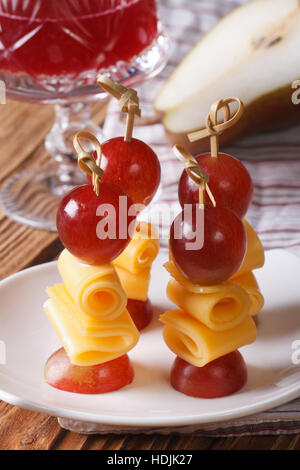 Les raisins rouges et fromage sur les brochettes sur une plaque verticale. Banque D'Images