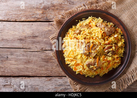 Délicieux pilaf asiatiques sur une plaque horizontale marron. Vue de dessus, style rustique Banque D'Images