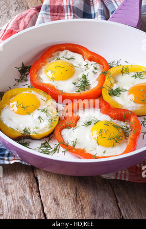 Oeufs au plat avec des poivrons rouges et jaunes dans une casserole close-up vertical. Banque D'Images