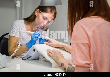 Femme dans un salon de manucure recevant une manucure par une esthéticienne Banque D'Images