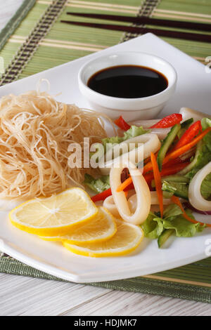 Salade de légumes asiatiques avec les calmars et les nouilles de riz et une assiette de près. La verticale Banque D'Images