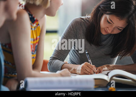 Jeune femme prise de notes à partir de livres pour son étude. Les élèves assis à table avec des livres Préparer travail scolaire. Banque D'Images