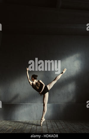 Ballerine souple s'étendant dans le noir studio lumineux Banque D'Images