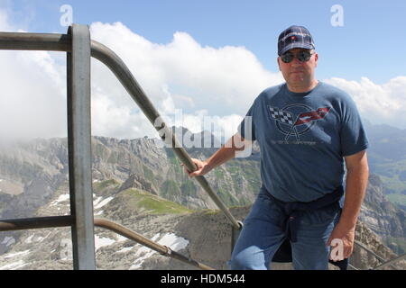 Un touriste américain portant un t-shirt Corvette monte les dernières marches à la plate-forme d'observation sur le sommet de la montagne Säntis dans les Alpes suisses. Banque D'Images