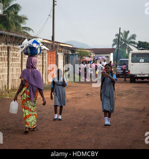 Femme et les étudiants dans l'uniforme scolaire dans la rue de Kenema, Sierra Leone Banque D'Images