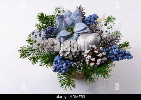 La verdure de Noël avec decor et poinsettias en soie bleue. Arrangement de fleurs de Noël artificiel avec des pommes de pin et branches de sapin. Chri Banque D'Images