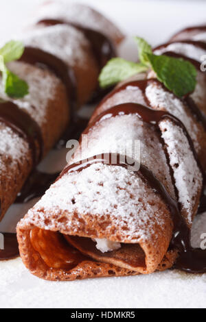 Des crêpes au chocolat avec sauce à la menthe et macro sur une plaque verticale. Banque D'Images