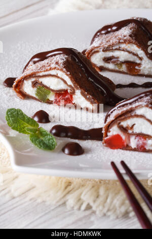 Crêpes au chocolat japonais rouleaux avec du fromage et des fruits sur une assiette blanche close-up vertical. Banque D'Images