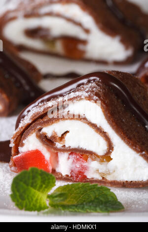 Crêpes au chocolat rouleau avec du fromage et des fruits sur une plaque verticale macro. Banque D'Images