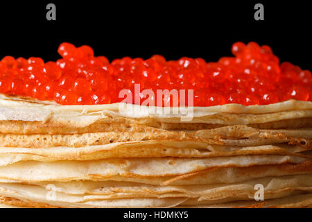 Pile de crêpes avec du caviar rouge isolé sur fond noir macro Banque D'Images