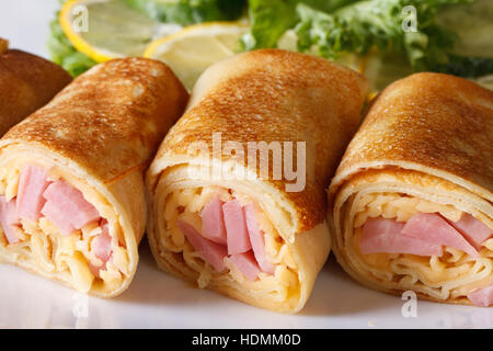 Crêpes farcies de jambon et de fromage sur une assiette blanche macro horizontale. Banque D'Images