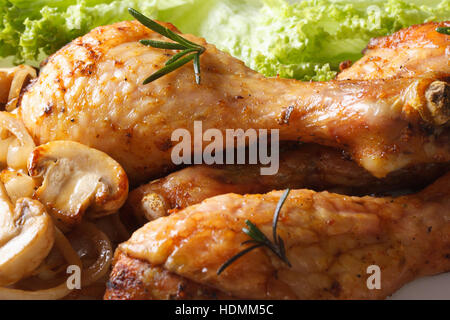 Cuisses de poulet frit aux champignons et la laitue sur une assiette horizontale macro. Banque D'Images