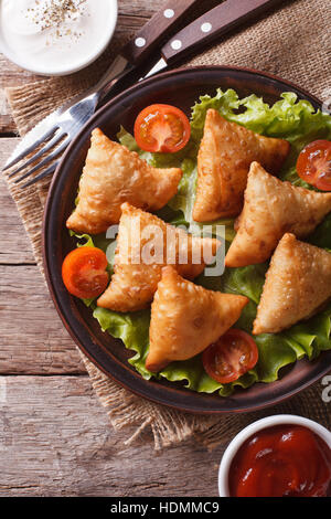 Samosas sur une plaque avec la sauce et les tomates libre. vertical Vue de dessus, style rustique Banque D'Images