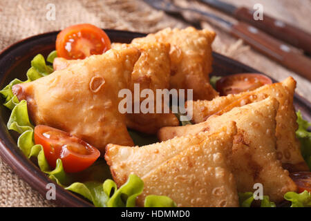 Samosas sur une plaque avec les tomates et la laitue sur une table de bois horizontal close-up. Banque D'Images