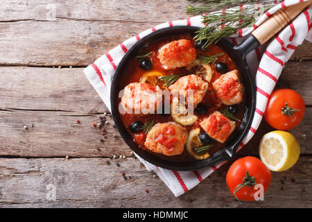 Poissons en sauce tomate aux Olives et citron dans une poêle. Vue du dessus horizontale Banque D'Images