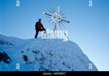 Homme debout à côté du sommet cross sur Mt. Steinerner Jaeger, pré-Alpes près de Reichraming en hiver, Haute Autriche, Autriche Banque D'Images