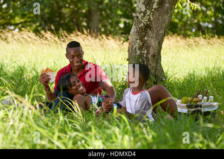 Happy black couple avec fils dans city park. African American Family avec jeune homme, femme et enfant de manger des aliments au cours de pique-nique. Banque D'Images