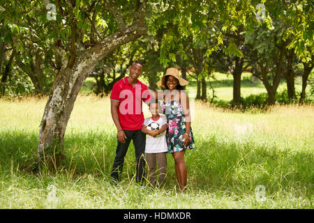 Heureux les noirs en parc. African American Family avec de jeunes mère, père et fils s'amusant avec le football. Portrait d'homme, femme et enfant avec le soccer b Banque D'Images