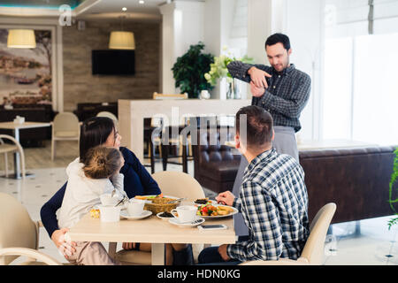 La famille, la parentalité, la technologie, les gens heureux concept - mère, père et petite fille qui a demandé à prendre une photo par serveur smartphone Blackberry Banque D'Images