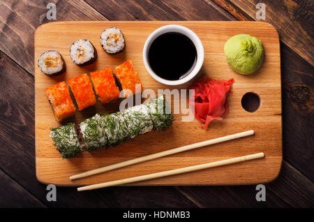 Rouleaux de sushi avec de la sauce soja, gingembre et wasabi sur une planche à découper close-up Banque D'Images