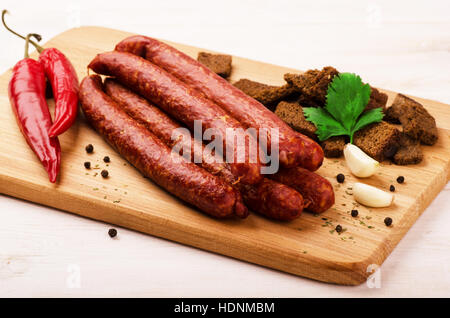 Salami fumé saucisse avec l'ail, les croûtons et les piments on cutting board Banque D'Images