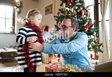 Père avec daugter decorating Christmas Tree, une tresse d'enrubannage Banque D'Images