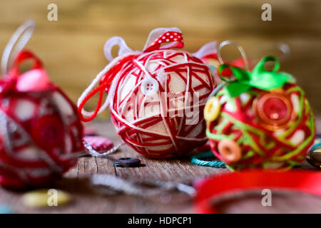 Libre de quelques boules de noël faites à la main, fait avec ribbon bow, cordes et boutons de couleurs différentes, sur une surface en bois rustique Banque D'Images