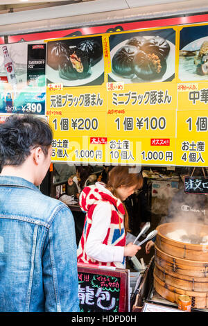 Le Japon, Kobe Nankinmachi, Chinatown. L'homme japonais d'acheter du Chinois dim sum avec blocage de port du vendeur Union Jack dessus. Le bol de dim-sum. Banque D'Images