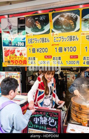 Le Japon, Kobe Nankinmachi, Chinatown. L'homme japonais d'acheter du Chinois dim sum avec blocage de port du vendeur Union Jack dessus. Le bol de dim-sum. Banque D'Images