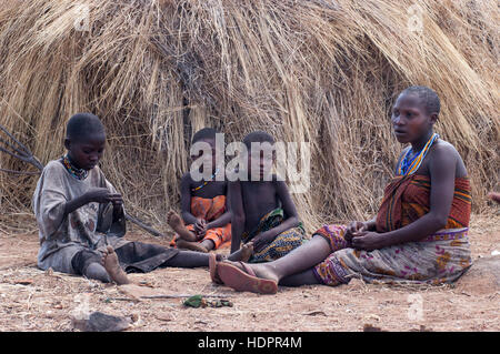 Hadzabe femme assise avec trois enfants en face d'une hutte d'herbe,ou le lac Eyasi, Hadza, Tanzanie Banque D'Images