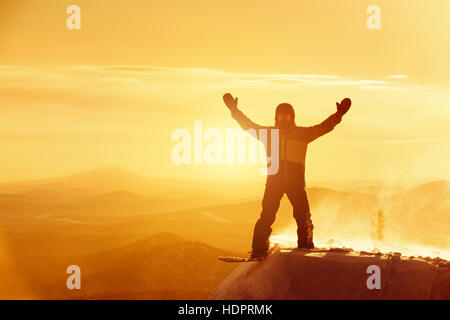 Snowboarder heureux gagnant gagner poser ski resort sunset Banque D'Images