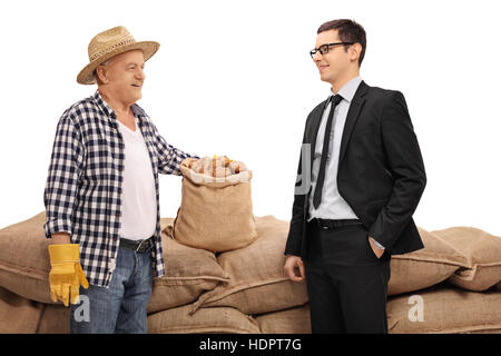 Agriculteur âgé et un jeune homme debout devant un tas de sacs de toile isolé sur fond blanc Banque D'Images