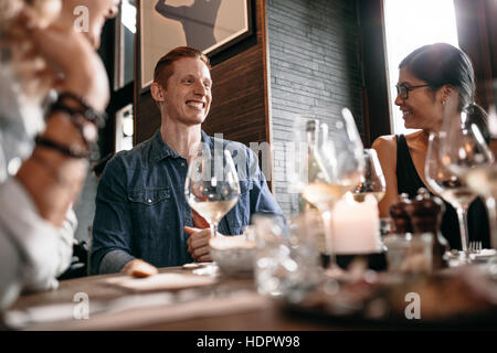 Jeune homme heureux avec des amis au café. Les jeunes de dîner dans un restaurant. Banque D'Images