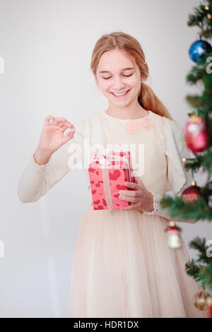 Happy girl déballage cadeaux de Noël debout derrière un arbre Banque D'Images