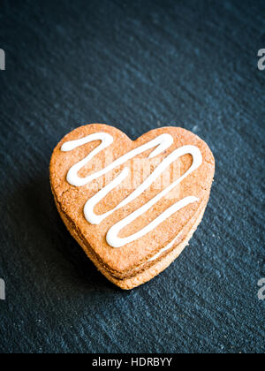 Heart-shaped Christmas gingerbread cookies disposées en une pile sur un fond sombre. Banque D'Images