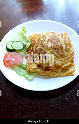 Nasi Goreng Pattaya ou connu comme omelette farcie de riz frit servi sur une plaque blanche sur table en bois Banque D'Images